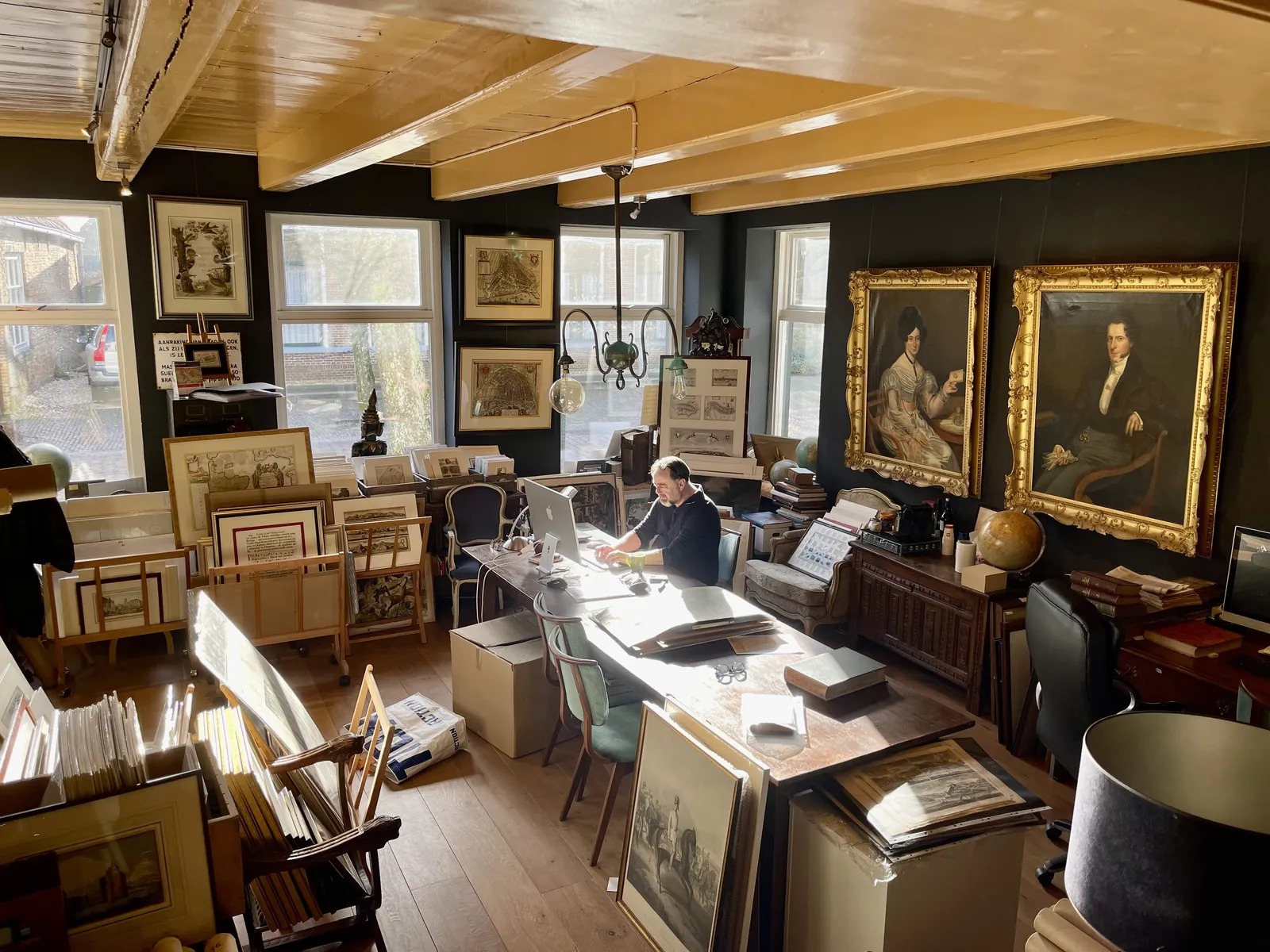 Bartele Santema at work in the Langweer gallery, among framed maps, prints and portraits
